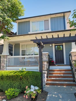 A perfect neighbourhood. The porch and entrance of a lovely residential house against a blue sky background