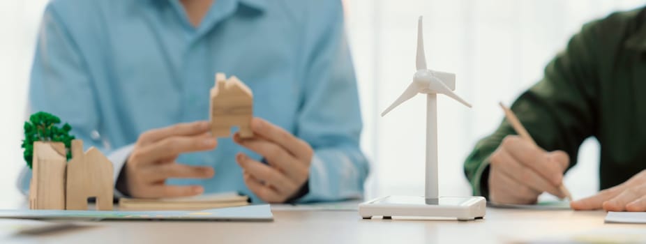 Business people invest in green business plan at meeting room on table with house model and wind mill placed represented eco house and renewable energy. Closeup. Delineation.