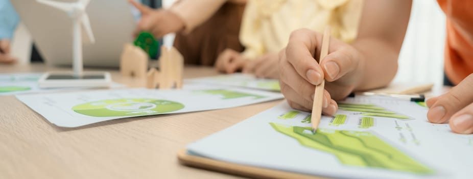 Windmill model represented using renewable energy placed during presenting green business on table with wooden block and environmental document scatter around. Closeup. Delineation.