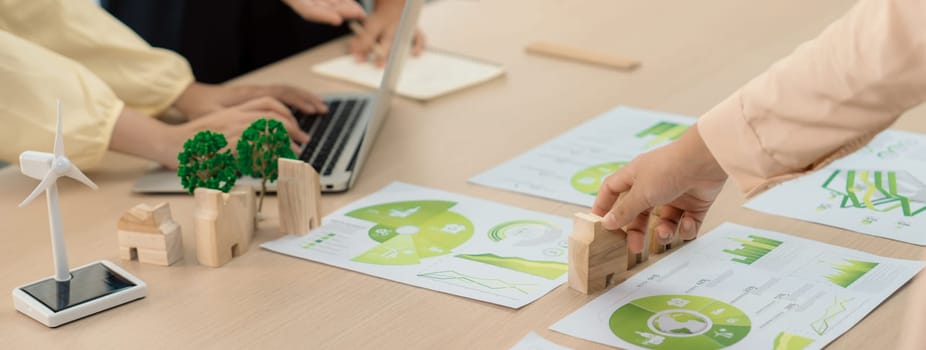 Environmental documents and a windmill model representing the use of clean energy are scattered on the table during a green business discussion about investing in clean energy. Closeup. Delineation.