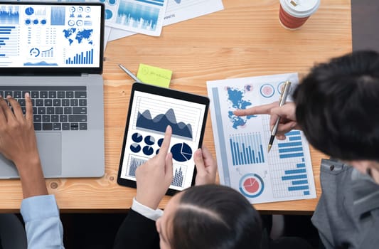 Multiracial analyst team use BI Fintech software to analyze financial data on meeting. Top view finance dashboard data display on laptop screen with analyzed chart for marketing indication. Concord