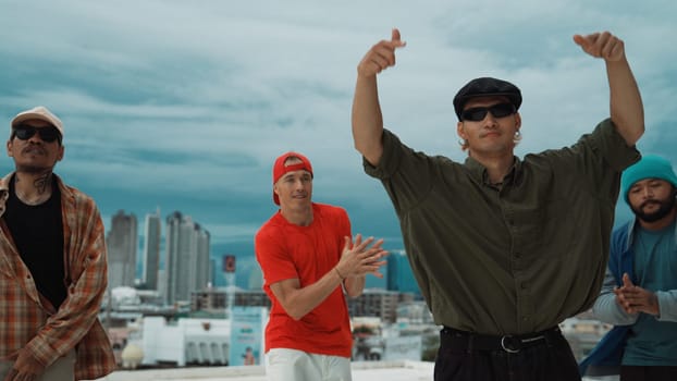 Skilled multicultural street dancing group pose at camera at roof top while moving to the rhyme and music. Young people or teenager moving to funky music, break dance. Outdoor sport 2024. Endeavor.