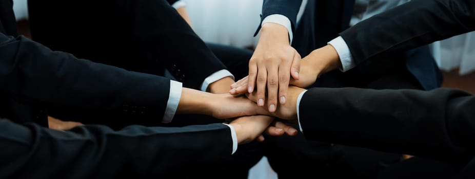 Office worker team stacking hand together symbolize successful group of business partnership and strong collective unity teamwork in community workplace in panoramic banner. Shrewd