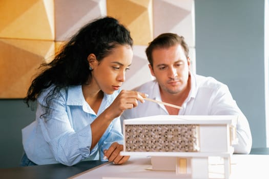 Cooperative skilled architect engineer team discussion about house construction while measuring house model at modern office. Team work, working together and creative design concept. Manipulator.