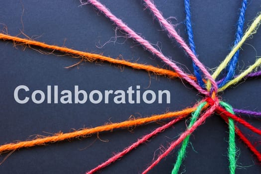 Collaboration concept. Colored threads are connected together and inscription.