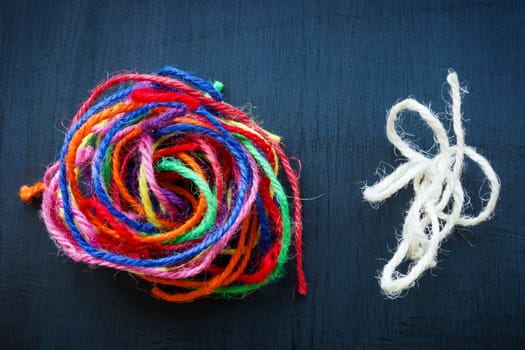 A ball of colored threads and regular one next to it as a symbol of teamwork and collaboration.