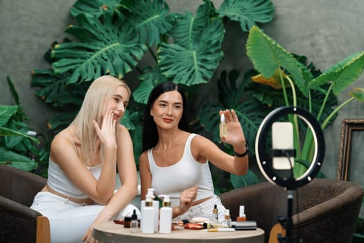 Two beautiful content creator making natural beauty and cosmetic tutorial on green plant garden video. Beauty blogger showing how to beauty care to social medial audience using selfie stick . Blithe