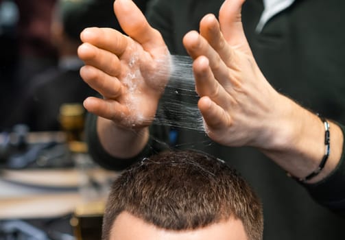 A barber deftly styles a clients hair with powder in the barbershop.