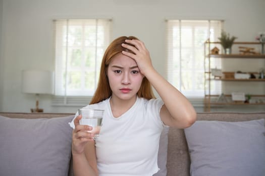 A young Asian woman in the living room was suffering from a headache due to accumulated stress due to health problems and lifestyle problems causing stress disorder..