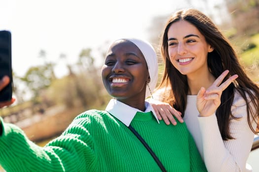 two young female friends smiling happy while taking selfie photo with mobile phone, concept of friendship and modern lifestyle