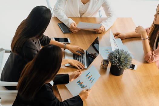 Businesswoman in group meeting discussion with other businesswomen colleagues in modern workplace office with laptop computer and documents on table. People corporate business work team concept. uds