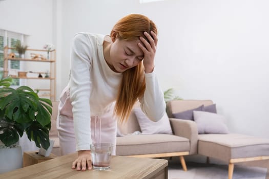 A young Asian woman in the living room was suffering from a headache due to accumulated stress due to health problems and lifestyle problems causing stress disorder..