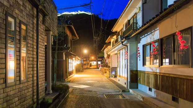 Empty narrow road in Takeda at night with lit castle on hill over town. High quality photo