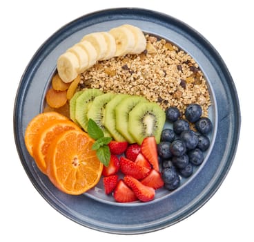 Granola with strawberries, kiwi, banana and blueberries in a round plate. Top view