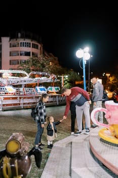 Little girl hands a carousel ticket to an usher while standing next to her mother. High quality photo