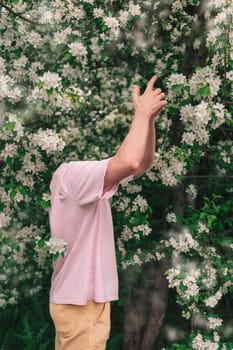 Creative male portrait with mirror in a blooming apples spring garden