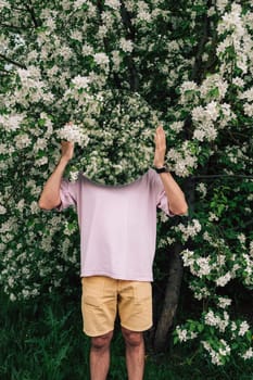 Creative male portrait with mirror in a blooming apples spring garden