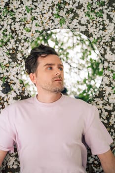 Creative male portrait with mirror lying in the ground in a blooming apples spring garden