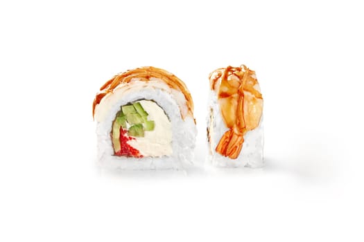 Closeup of shrimp-topped sushi roll drizzled with tangy sauce, filled with soft cream cheese, tobiko and crisp cucumber, presented isolated on white background. Japanese style snack