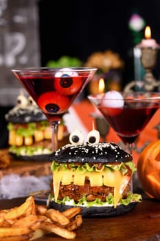 Monster Burger. Black bun, juicy beef cutlet, lettuce, onion, tomato and cheese in the shape of teeth, mozzarella eyes with olives. Definitely a pick-me-up and a perfect Halloween party appetizer.