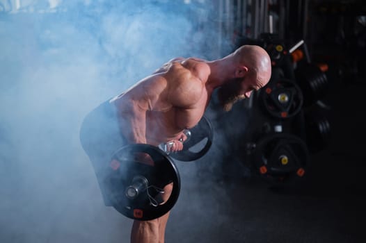 Caucasian bald topless man doing an exercise with a barbell in the gym