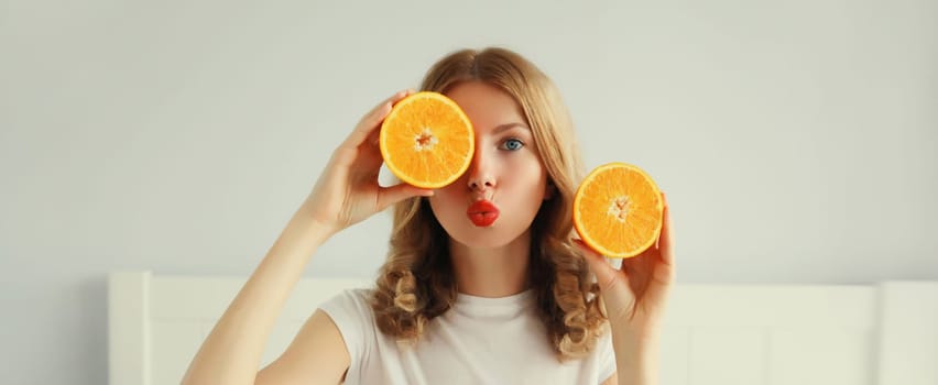 Summer, nutrition, diet and vegetarian concept. Happy healthy cheerful young woman with slices of orange fruits in white room at home