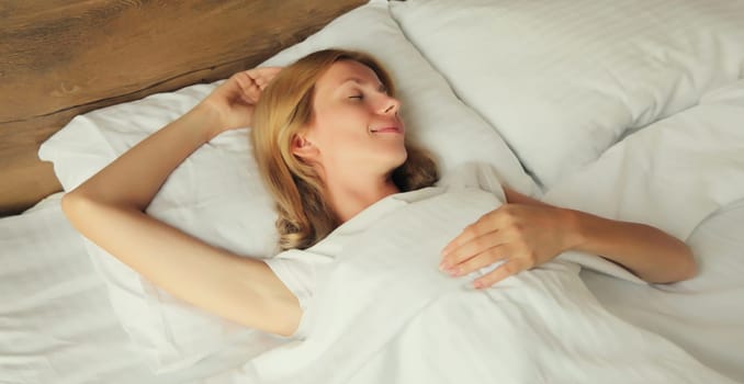 Young woman sleeping lying in bed on white soft comfortable pillow in bedroom at home