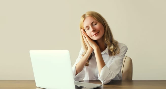 Tired overworked sleeping woman employee while working with laptop sitting at desk in office in morning