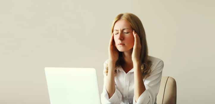 Tired overworked woman employee suffering from headache, migraine, working with laptop sitting at desk in office in morning