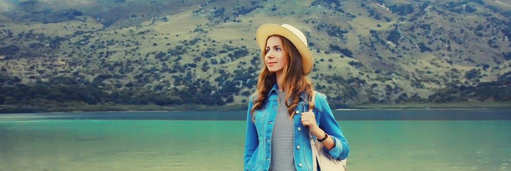 Summer vacation, young woman tourist in straw hat with backpack on lake and mountains background. Greece, island Crete