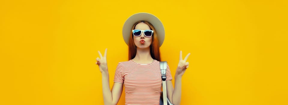 Portrait of stylish young woman posing in summer straw hat on bright yellow studio background