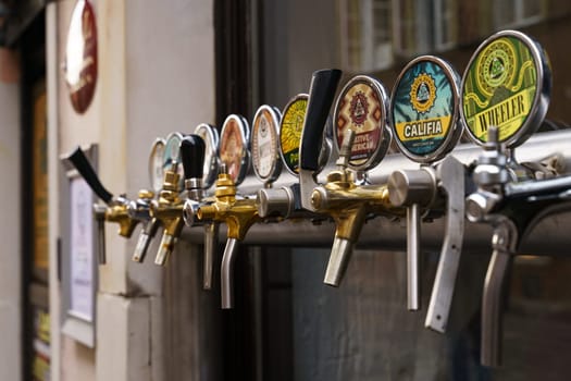 Warsaw, Poland - August 6, 2023: A line of draft beer taps installed on the exterior wall of a pub on the street.