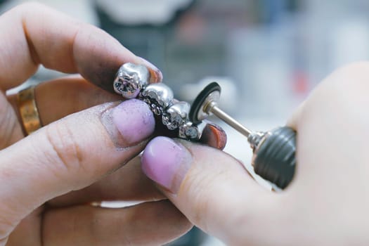 A dental technician is seen working on a toothbrush component in a room, using tools and equipment to manufacture the metal prosthesis.