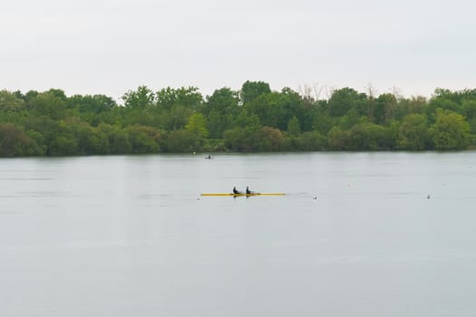 Bordeaux, France - April 26, 2023: Two individuals are rowing a boat on a vast lake.