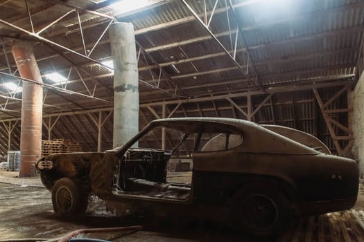 Old disassembled car in an abandoned factory.