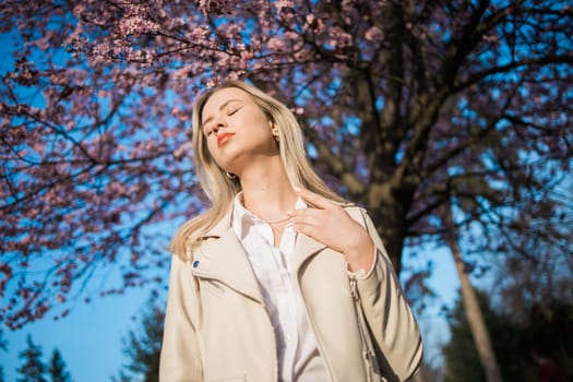 Woman with cherry flowers surrounded by blossoming trees copy space. Beauty and seasonal change and spring bloom season concept