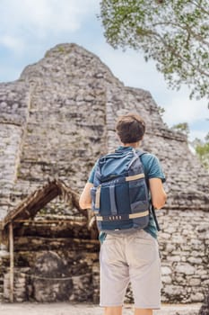 Man tourist at Coba, Mexico. Ancient mayan city in Mexico. Coba is an archaeological area and a famous landmark of Yucatan Peninsula. Cloudy sky over a pyramid in Mexico.