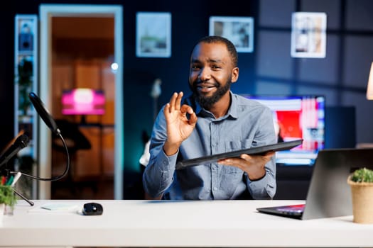 Content creator presenting gaming keyboard to subscribers, giving guarantees about precision and power. Tech expert showing ok hand sign, happy about computer peripheral after testing it