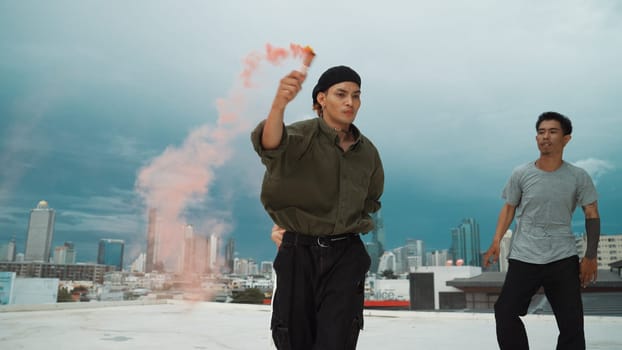 Group of multicultural hipster playing color flare at rooftop. Attractive street dancer holding colored smoke and perform break dance move to hip-hop music. Outdoor sport 2024. Endeavor.