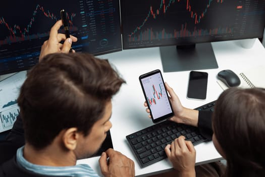 Top view focusing on phone discussing dynamic stock market in two business traders online website compare with pc screens in real time currency rate investment risk data at modern office. Postulate.