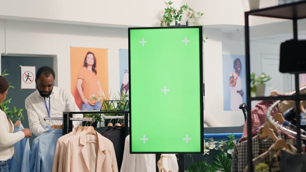 Green screen kiosk in luxury clothing shop with elegant formalwear clothes available for customers to design their own outfits. Chroma key digital display in fashion boutique ready to be used by clients