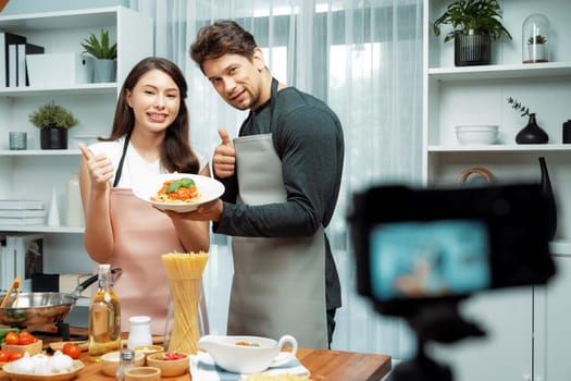 Couple chef influencers completely cooked spaghetti with meat topped with tomato sauce special dish recording on camera with live chanel. Concept of serving healthy food at modern home. Postulate.