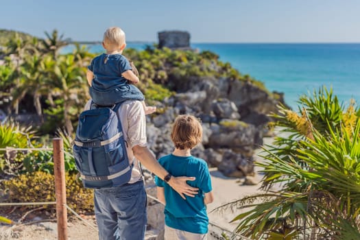 Father and two sons tourists enjoying the view Pre-Columbian Mayan walled city of Tulum, Quintana Roo, Mexico, North America, Tulum, Mexico. El Castillo - castle the Mayan city of Tulum main temple.