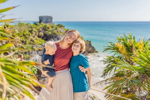 Mother and two sons tourists enjoying the view Pre-Columbian Mayan walled city of Tulum, Quintana Roo, Mexico, North America, Tulum, Mexico. El Castillo - castle the Mayan city of Tulum main temple.