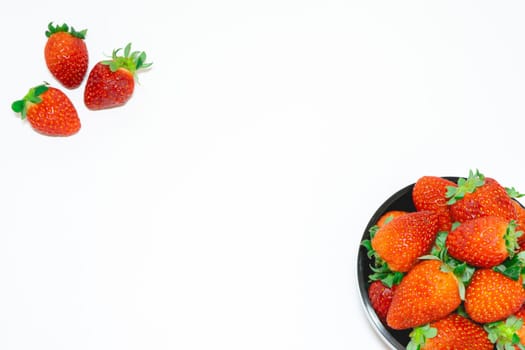 black bowl with fresh strawberries on a white background.