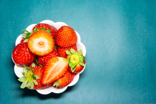 A bowl with peaces of strawberries on a blue background.
