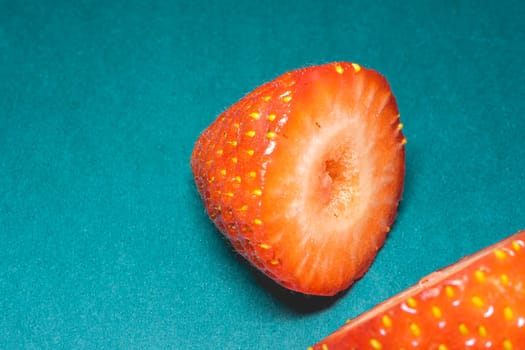 Peaces of fresh strawberries on a blue background.