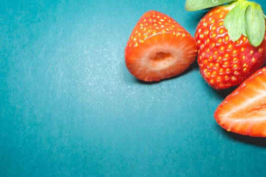 Peaces of fresh strawberries on a blue background.