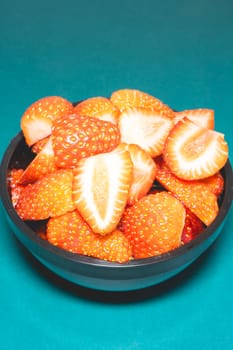 A bowl with peaces of strawberries on a blue background.