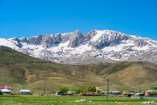 The lush green Sobucimen plateau in spring and the mountains with some melted snow behind.